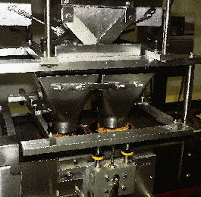 Near the head of the line, the black bowls in their carrier plates pass beneath the twin hoppers (left) of the filling station.
