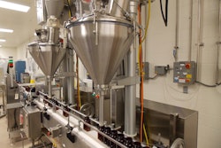 TWO FILLERS. Bottles on the conveyor line pass underneath the two Spee-Dee fillers. After the bottles are filled they are sealed and prepped for shipping.