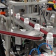 BOTTLE TRACKER. As bottles travel up to the BottleTracker by conveyor, an outsert machine applies a topsert on top of the bottles. This is a folded leaflet applied to the top of each bottle that contains information related to the product.