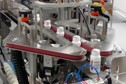 BOTTLE TRACKER. As bottles travel up to the BottleTracker by conveyor, an outsert machine applies a topsert on top of the bottles. This is a folded leaflet applied to the top of each bottle that contains information related to the product.