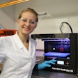 Katazyna Pietrzak, a student in Alhnan research team holding a 3D printed theophylline tablet made of 100% pharmaceutical-grade materials.