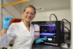 Katazyna Pietrzak, a student in Alhnan research team holding a 3D printed theophylline tablet made of 100% pharmaceutical-grade materials.