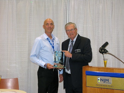 NJM Packaging president Michel Lapierre receives a commemorative plaque from Charles Yuska, president and CEO of PMMI.