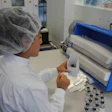 MANUAL PACKING. An operator places a glass vial into the clinical trials carton.