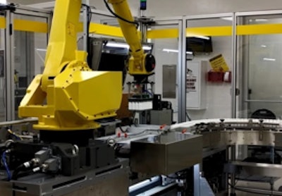 Fanuc robotic arm presenting camera with bottles.
