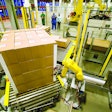 Figure 4: This end-of-line photo shows robots adding corner boards prior to stretch wrapping a load of pharmaceutical products. This system was part of an overall case packing and palletizing turnkey solution. The robots are working in a caged cell to ensure worker safety.