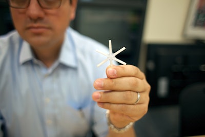 The star-shaped drug delivery device, held here by Giovanni Traverso, a Koch Institute research affiliate, can be folded inward and encased in a smooth capsule. Once ingested, the device delivers a full drug payload gradually over weeks or even months. Photo Credit: Melanie Gonick