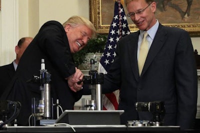 Trump trying to break a medicine vial with a vise with Corning CEO, Wendell Weeks / Image: UPI
