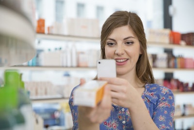 A consumer scans a coded pharmaceutical carton at a pharmacy.