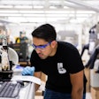 Graduate student research assistant in the Shtein lab, Siddharth Borsadia, prints fluorescein crystals onto a cooled glass plate using organic vapor jet printing. (Photo by Levi Hutmacher, Michigan Engineering.)