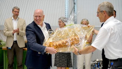 Hans Buehler, the Managing Director of the Optima Group handed over a bread plait in the shape of a key to Gerhard Breu.
