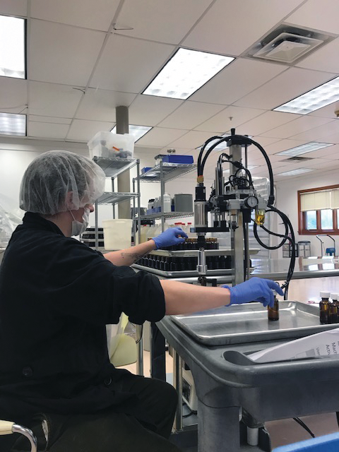 A UBIX operator uses a semi-automated machine to cap bottles.