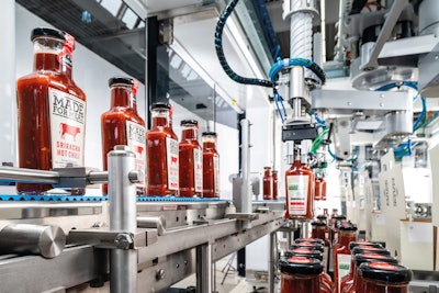 Two pick-and-place robots pick two bottles at a time from the product conveyor and place the desired number of bottles to be packed on the Transmodul with the erected cases.