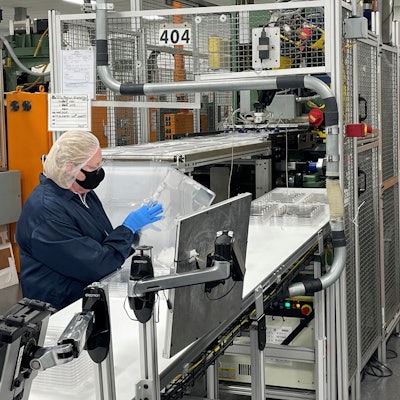 An inspector checks every lid for quality at the end of the production line before packaging and sending to SiO2.