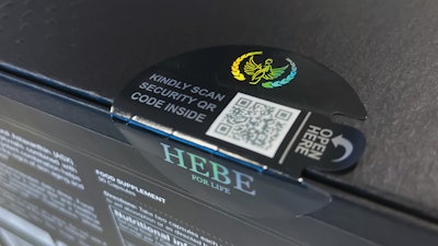 A holographically printed, tamper evident label with external QR code and die-cut tear strip spans the gap between shipper sidewalls and top.