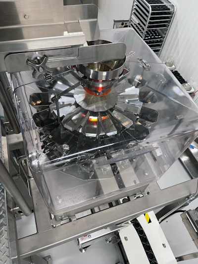 On a mezzanine, a product infeed conveyor introduces cannabis flower to a multihead combination scale.