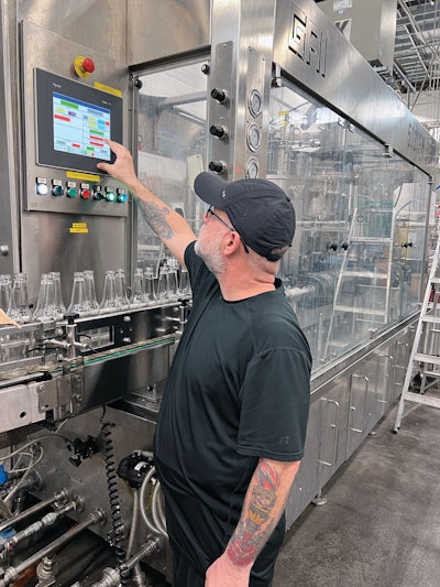An operator interacts with the HMI on the GAI monoblock bottle filler and crowner.