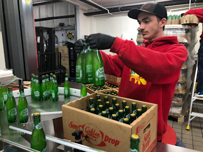 Filled and crowned bottles rotate on a Multi-Conveyor accumulation table before being inspected and hand-packed into cases.