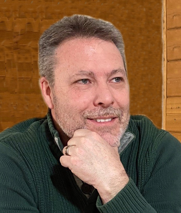 Middle-aged man in green sweater smiling and resting chin on hand