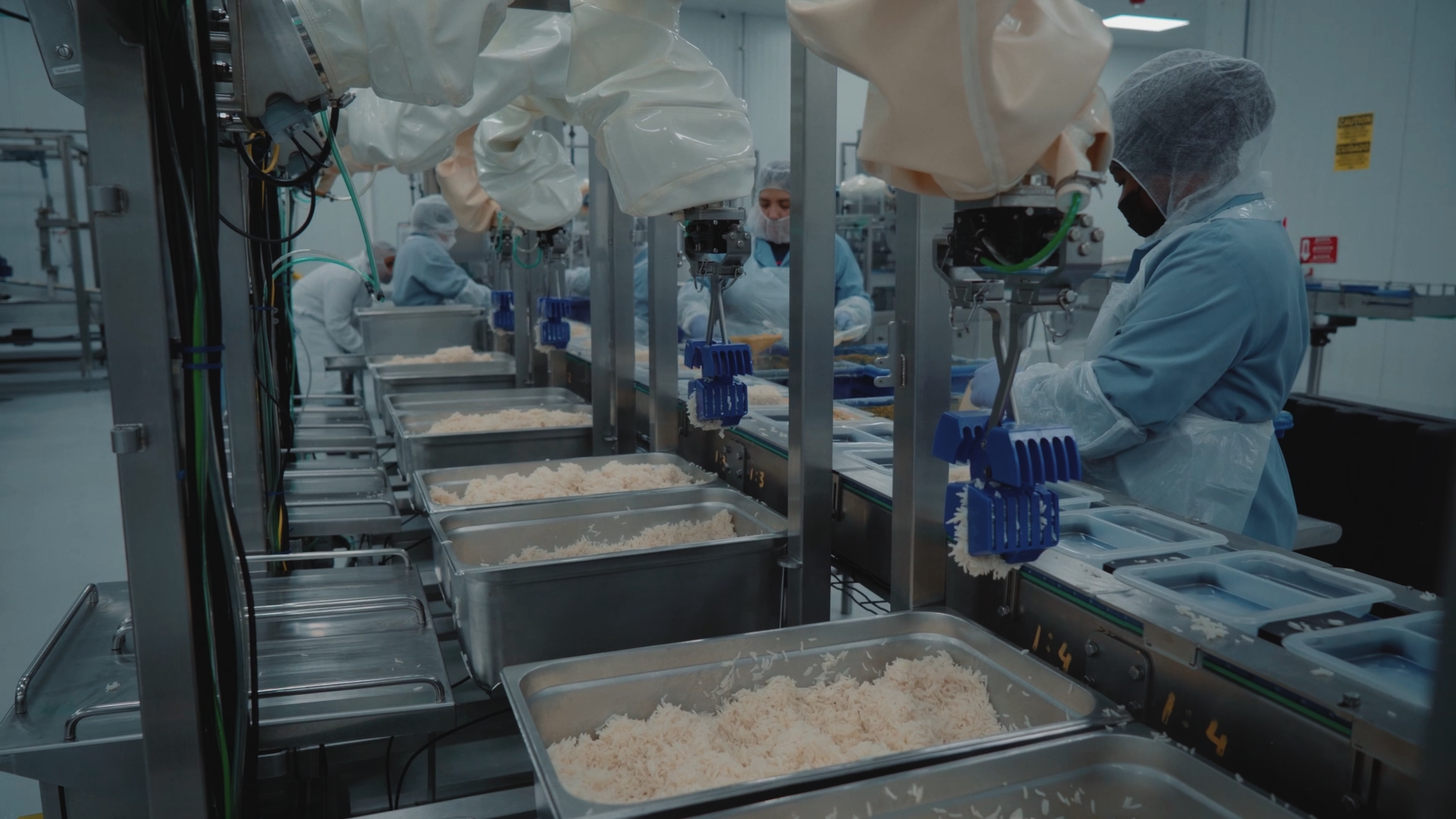 Food processing line with workers in sterile blue uniforms preparing ingredients