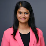 Professional woman in pink blazer smiling against gray background