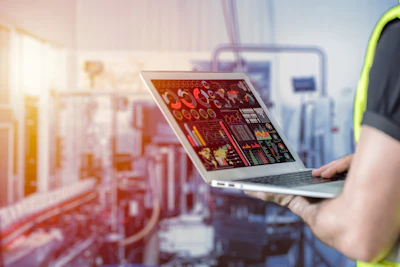 Laptop displaying industrial analytics dashboard in manufacturing facility