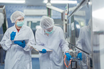 Two scientists in sterile white protective gear working in a medical laboratory