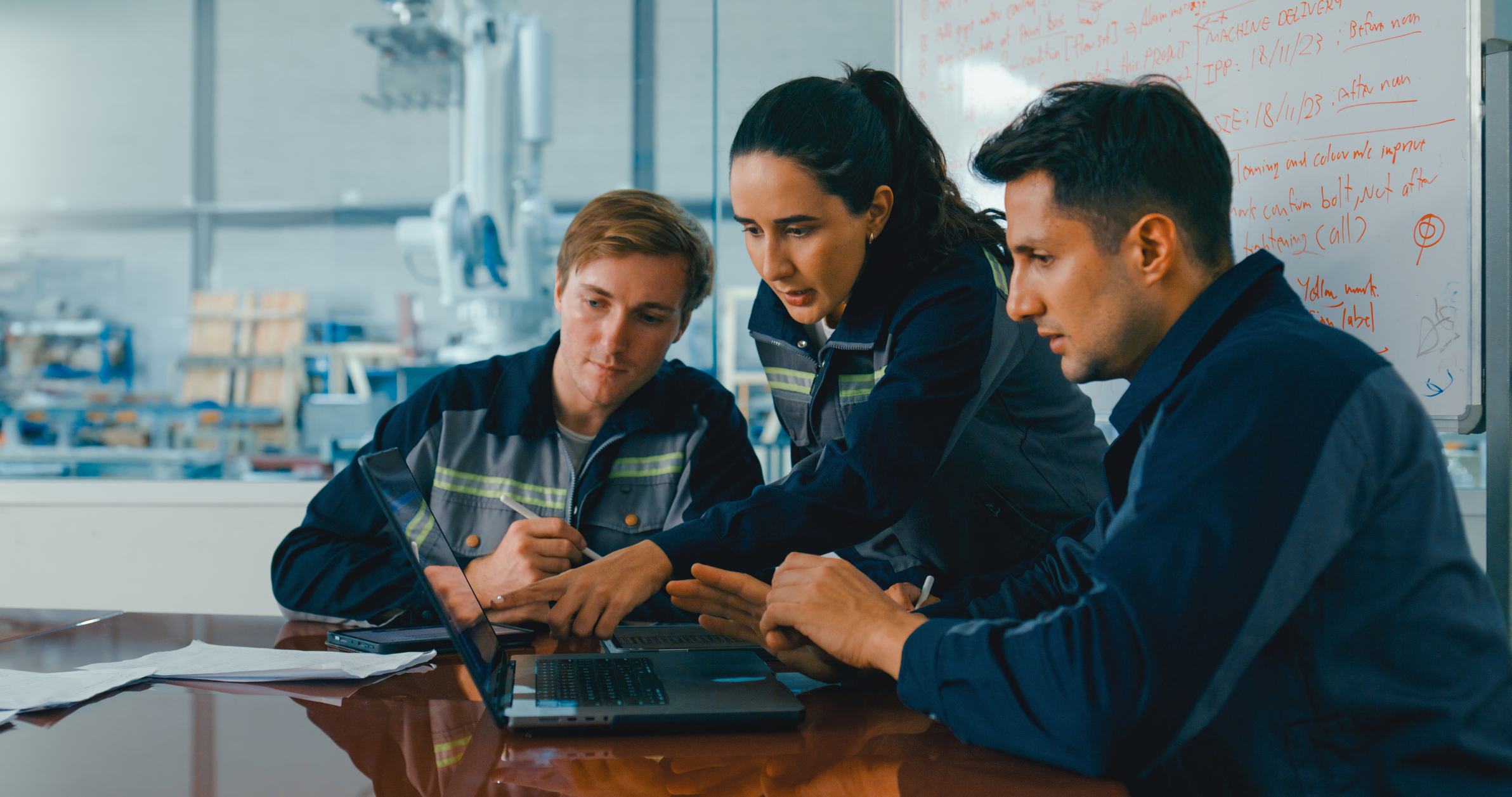 Three professionals collaborating on a laptop in a modern office workspace