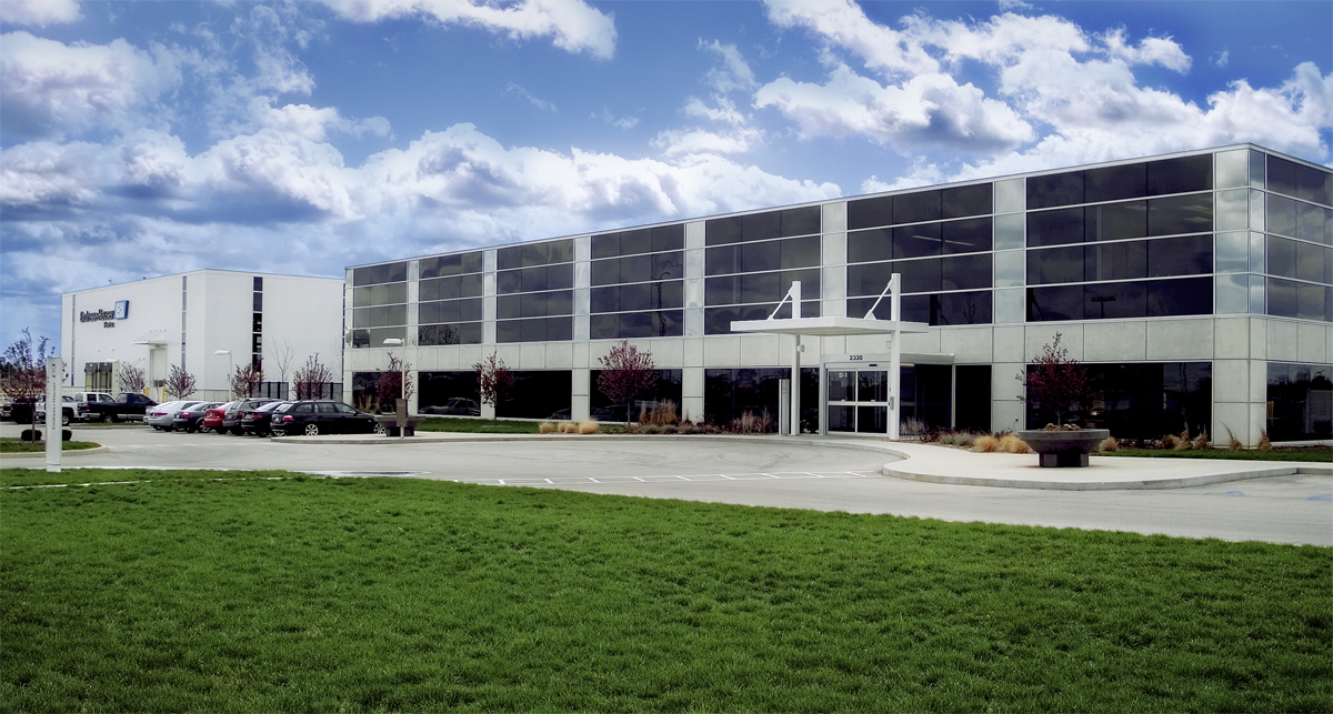 Modern two-story corporate office building with glass windows and parking lot