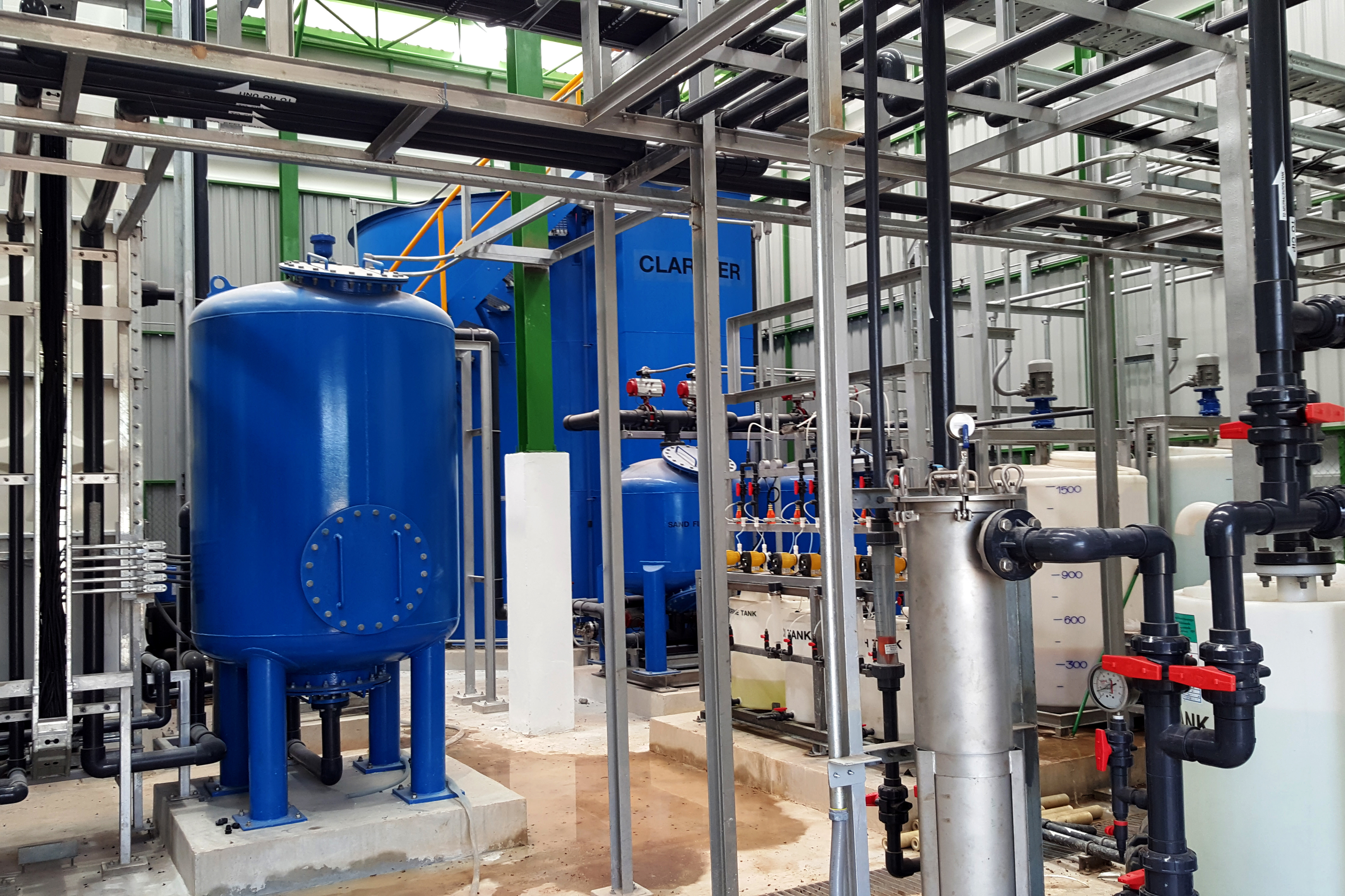 Industrial water filtration system with blue tanks and metal piping in a manufacturing facility