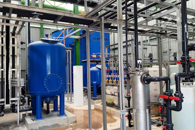 Industrial water filtration system with blue tanks and metal piping in a manufacturing facility