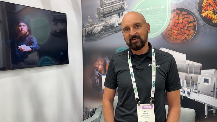 Bald professional at trade show booth with industrial equipment graphics