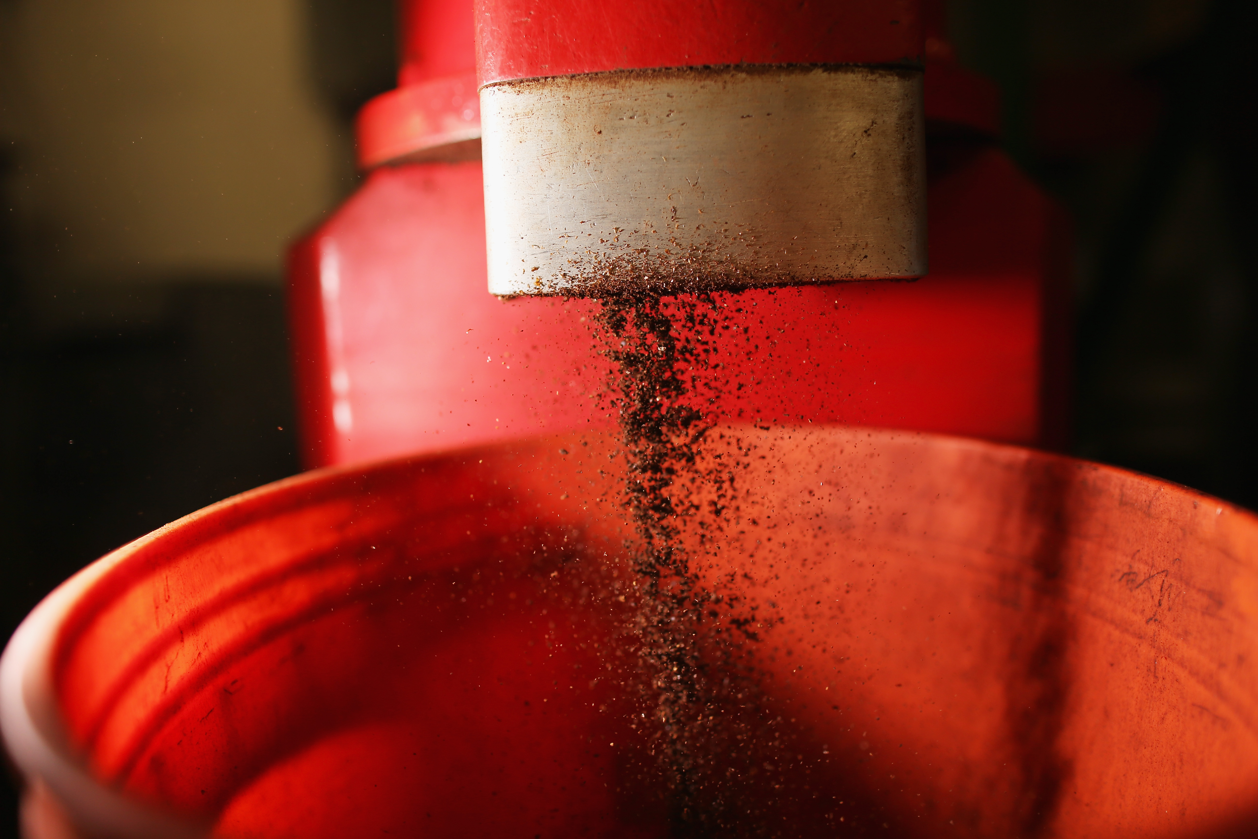 Black powder cascading from a red container against a blurred background