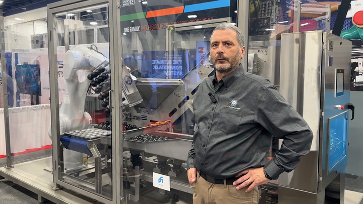 Industrial professional standing near robotic packaging machinery in manufacturing facility