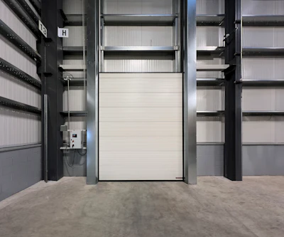 White industrial roller door inside metal-framed warehouse storage facility