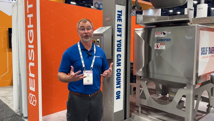 Trade show representative explaining equipment at industrial machinery exhibit