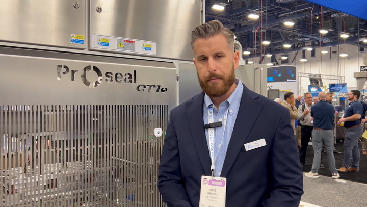 Professional standing near industrial Proseal packaging machine at trade show