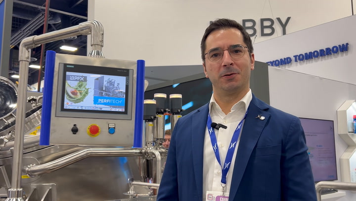 Professional in blue suit standing near industrial control panel at technology conference