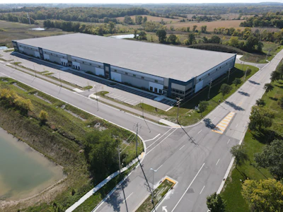 Aerial view of modern industrial warehouse complex surrounded by rural landscape