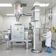 Pharmaceutical manufacturing clean room with industrial equipment and technician in white protective gear