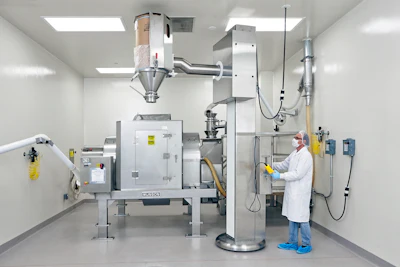 Drums containing each ingredient are lifted, aligned with the mixer's stationary inlet, and emptied&mdash;in a prescribed order according to the Master Batch Record.