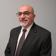 Mature professional in black suit and glasses with gray beard