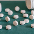 White pharmaceutical tablets scattered on green fabric near pill bottles