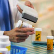 Pharmacist scanning prescription medication bottle near other pill containers