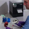 Laboratory technician scanning barcode labels with handheld scanner near label printers