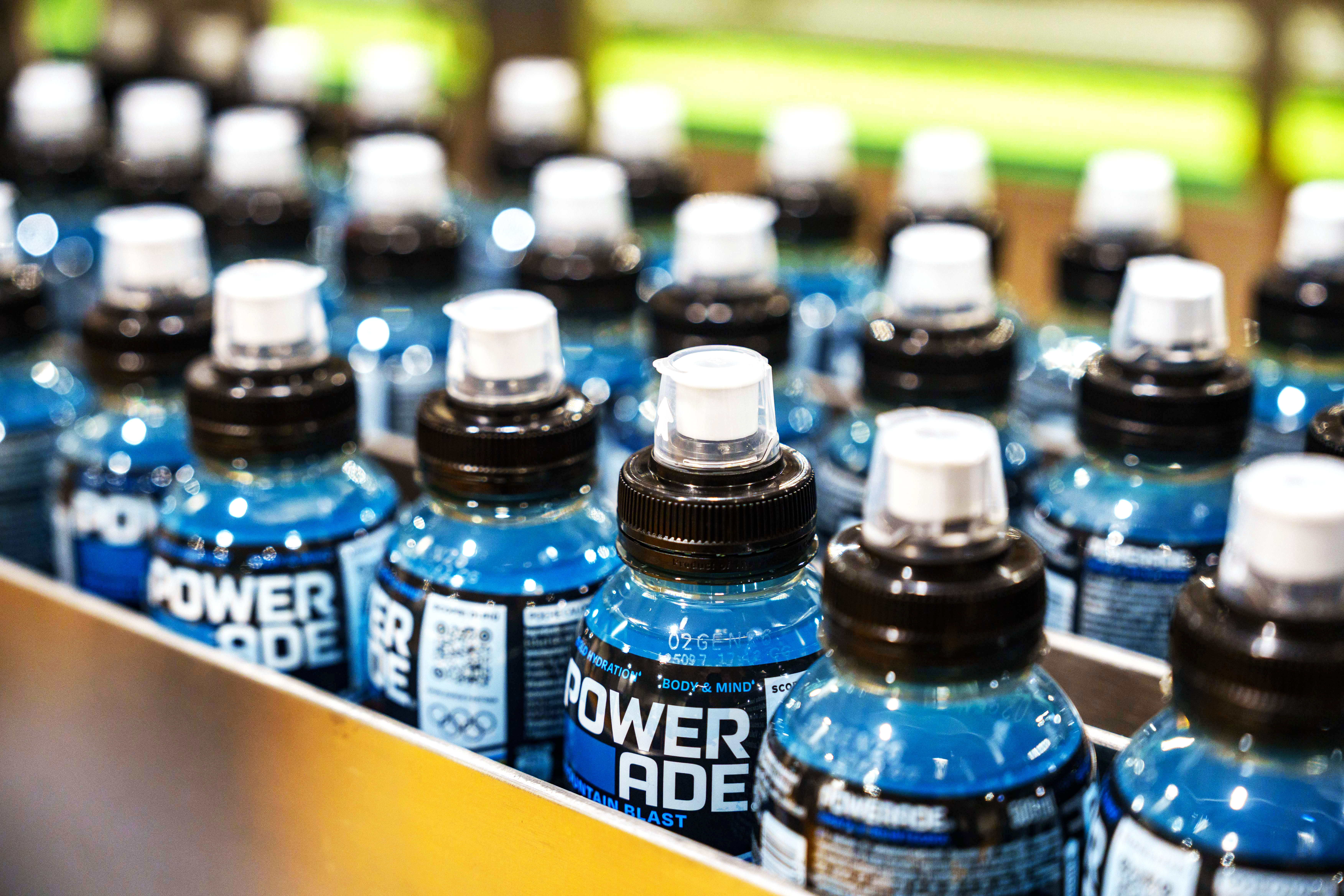 Blue Powerade sports drink bottles lined up in rows on a store shelf