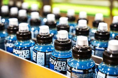 Blue Powerade sports drink bottles lined up in rows on a store shelf