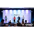 The Pack Out conference stage with four speakers presenting at a professional event