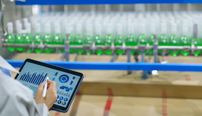 Tablet displaying analytics dashboard near industrial green bottling production line