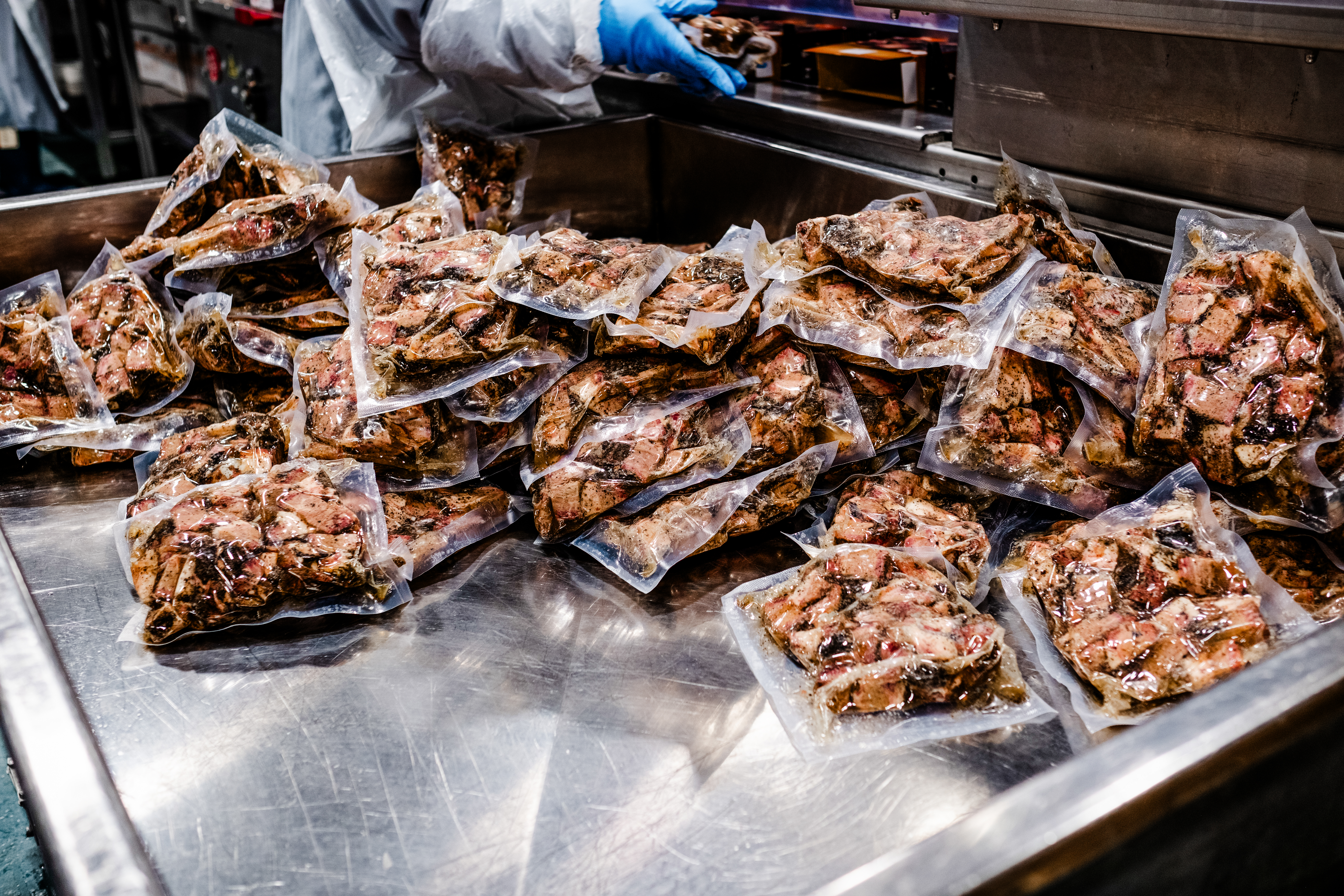 Sealed packages of cooked meat or protein on stainless steel preparation surface